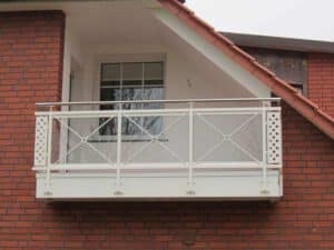 Weißer Balkon mit Glasscheiben und Edelstahlhandlauf an einem Wohngebäude