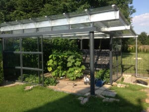 Gewächshaus mit solidem Trägerwerk, Glasseiten und Gabionen